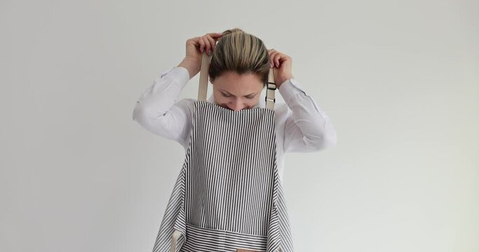 Female waiter or cook puts on gray apron. Chef clothes and aprons