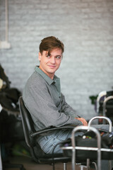 Handsome caucasian man sitting in hair salon aft.er hair cut with professional hairdresser.
