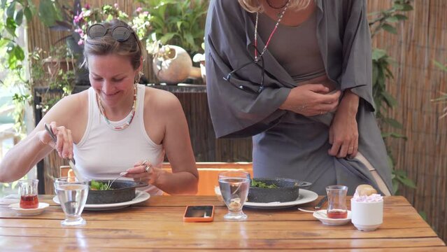 Two women in summer clothes having a fun breakfast in a restaurant in Turkey in the summer