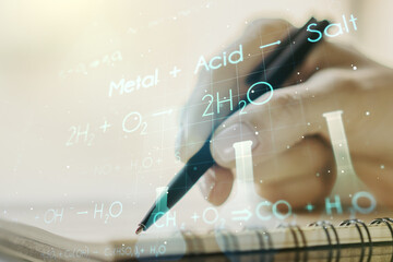 Creative chemistry hologram with man hand writing in notepad on background, pharmaceutical research concept. Multiexposure