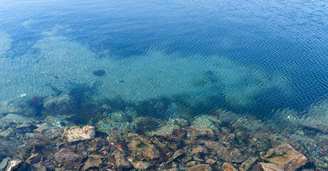 Fototapeta na wymiar Stones and pebbles visible through the water. Coastal feature.