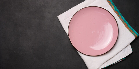 Empty pink ceramic plate on black table, top view