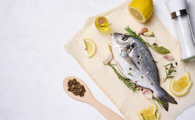 Raw whole dorado fish on white board and spices for cooking, top view on white table