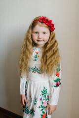 Portrait of a girl dressed in Ukrainian folk embroidered dress. A child with wreath of poppies on his head. National ethnic traditional costume or dress. Ukrainian girl, Ukrainian customs, traditions.