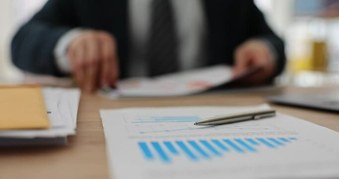 Businessman studying data chart and evaluating income statement in office. Strategic marketing analysis concept