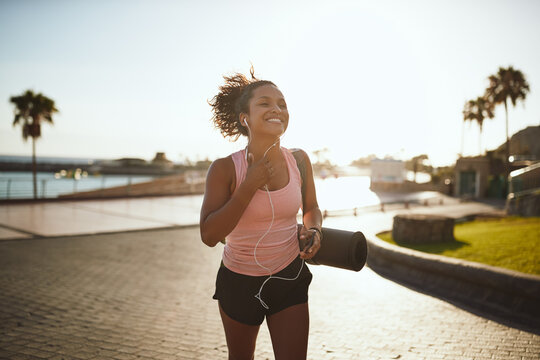 Sporty young woman walking on a promenade listening to music