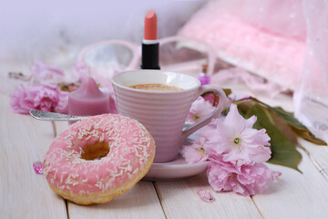 Obraz na płótnie Canvas cup with drink coffee cappuccino, hot chocolate with milk, pink donut, lipstick, sakura flowers, caffeine improves functioning of human brain, stimulates nervous system, health benefits and harms