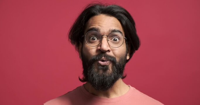 Closeup portrait of handsome bearded young man screaming in shock while celebrating achievement against isolated red background