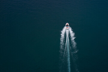 Drone view of a boat sailing. Large speed boat moving at high speed. Top view of a white boat sailing to the blue sea. Travel - image. Motor boat in the sea. © Berg