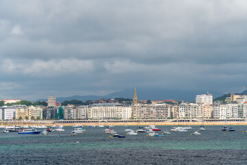 SAN SEBASTIAN, Spain July 08 2022: Beautiful San Sebastian - Donostia city. Situated in north of Spain, Basque Country. Famous travel destination. View of La Concha Bay. People at the beach. 