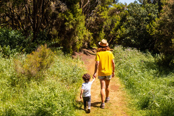 A mother with her son walking on the La Llania trekking trail in El Hierro, Canary Islands. lush green landscape