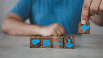 Fototapeta premium Healthcare and Insurance, medical concept. Man chooses icons healthcare medical symbols on wooden block cubes to plan Insurance for health with copy space used for health insurance conceptual.