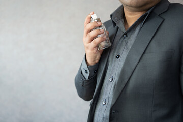 Fototapeta premium Smart Asian businessman spraying perfume fragrance to his neck area. Deodorant before go to working