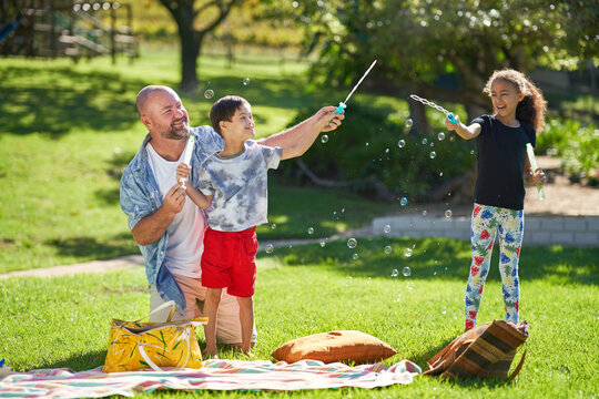 Happy family playing with bubbles in sunny summer park