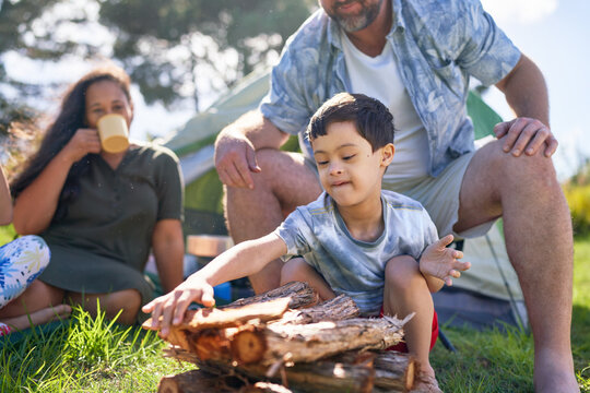 Father watching son with Down Syndrome stacking firewood at campsite