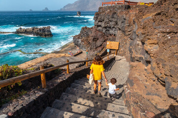 A mother with her son going down into the La Maceta rock pool on the island of El Hierro in the...