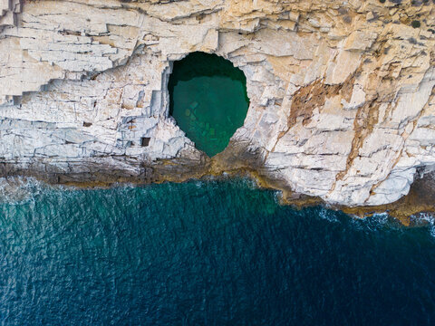Aerial view of Giola on the Greek island of Thassos. The natural swimming pool's crystal-clear turquoise waters, surrounded by rocky cliffs and lush greenery, create a mesmerizing visual spectacle.
