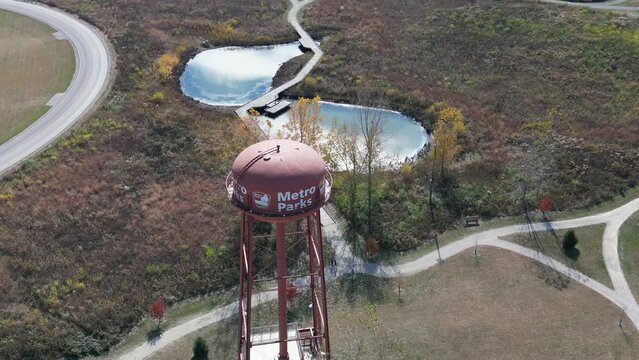 Aerial orbit of Metro Parks watertowner with ponds and greenery, Scioto Audubon Metro Park, Columbus, Ohio