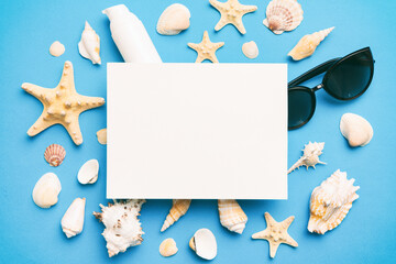 Naklejka na ściany i meble Summer time concept with blank greeting card and blank white paper on colored background. Seashells from ocean shore in the shape of frame separated with space for text top view