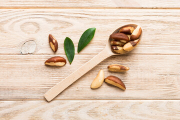 Fresh healthy brazil nuts in spoon on colored table background. Top view Healthy eating concept. Super foods