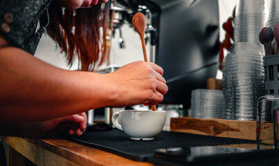 barista making coffee, the hand of a barista with a wooden spoon making or preparing coffee foam in a cup of coffee.
