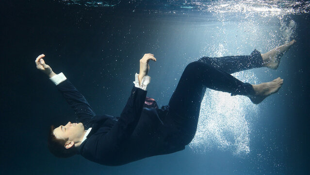 Businessman man in a suit, drowning under water.