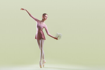 Fototapeta premium elegant young ballerina in pointe shoes dancing on a gentle green background