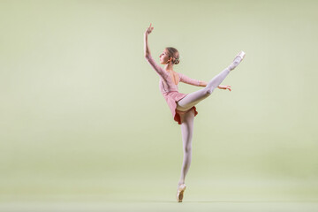 elegant young ballerina in pointe shoes dancing on a gentle green background