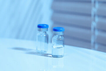 Vaccines are packed in glass vials on a table, cool toned image, blue color temperature