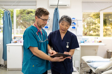 Man and woman health care workers  standing next to each other looking at a tablet in the clinic