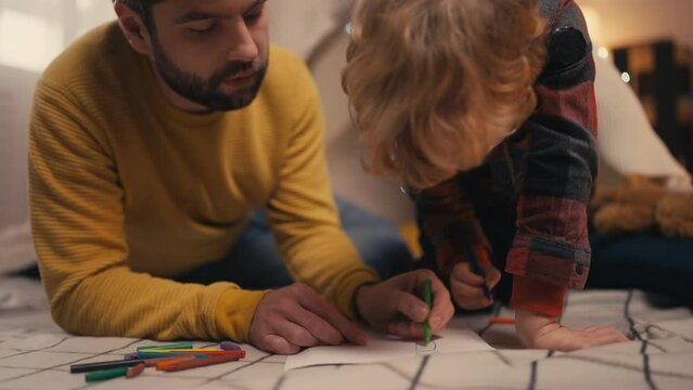 Father and little son drawing together in a blanket fort, happy family, hobby