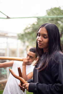 Aboriginal teenage girl with musical sticks in her backyard  with her brother