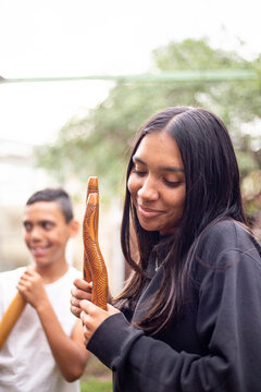 Aboriginal teenage girl with musical sticks in her backyard  with her brother