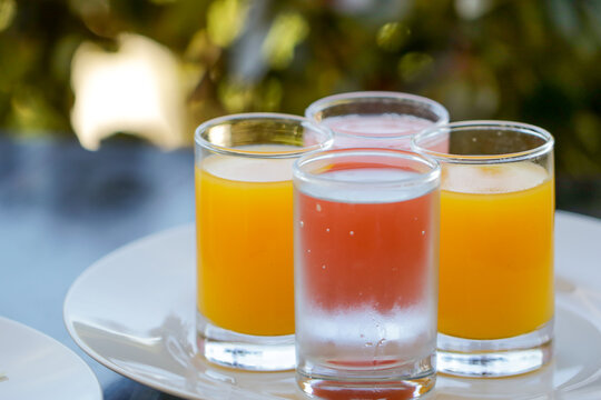 Close-up of four glasses of water, orange juice and guava juice on a plate