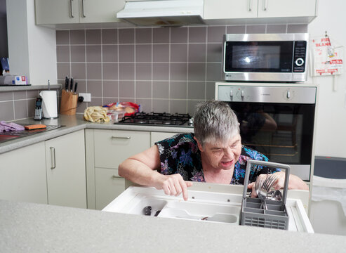 A Woman Seated On A Walking Frame, Sorting Cutlery In A Group Home