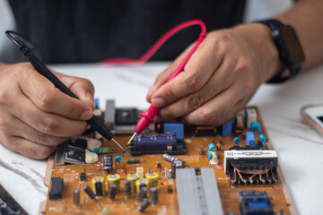 Technician using tool to measure circuit board, check and repair