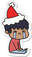 hand drawn sticker cartoon of a boy crying wearing santa hat