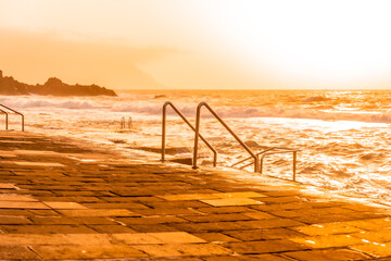 Fototapeta premium Stairs at sunset in the La Maceta rock pool on the island of El Hierro en la Frontera, Canary Islands