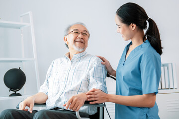 Happy positive asian nurse giving support and touching contented senior man with love. Nursing home...
