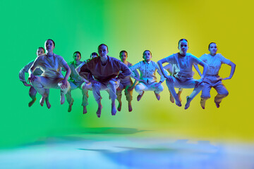 Portrait with group of teenagers, young dancers jumping up together over green and yellow gradient...