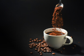 pouring coffee powder on coffee cup on dark background