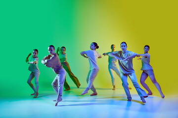 Group of teenagers, young dancers emotionally dancing together on gradient background in neon...