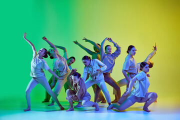 Dance team of young adorable girls moving to the beat of the music on gradient background in neon light. Improvisation performance