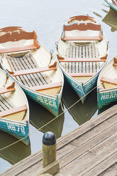 Looking down on four row boats tied to a wooden dock