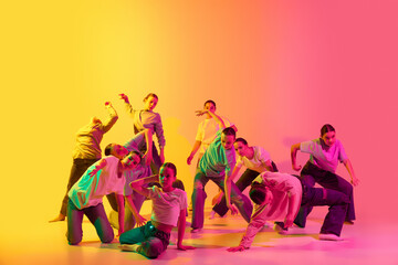 Group of young people, girls dancing contemp with different pose against gradient background in neon light. Modern freestyle dance