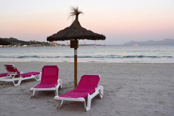 Sun loungers with umbrella on the sandy beach of Alcudia, Mallorca