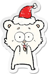 excited teddy bear hand drawn distressed sticker cartoon of a wearing santa hat