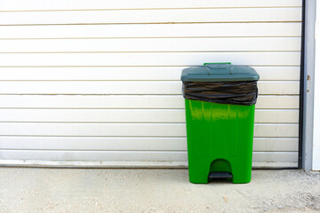 Green plastic garbage container standing in the street