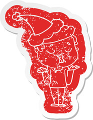 quirky cartoon distressed sticker of a man talking and shrugging shoulders wearing santa hat