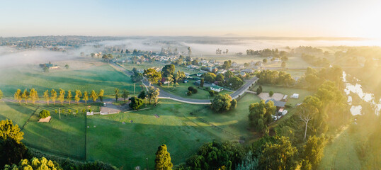 Warm morning sunlight chasing away fog from hobby farm paddocks near country town